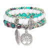 Close up of a multi strand beaded bracelet with a silver tree pendant
