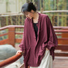 Woman wearing a loose maroon linen jacket with frog buttons outdoors