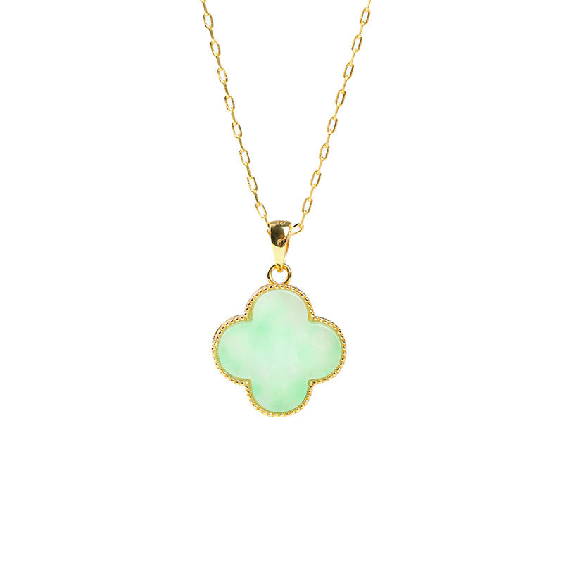 Close up of green four leaf clover pendant on gold chain