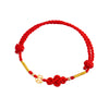 Close-up of a red braided bracelet with a Ruyi knot and gold coin charm on a white background