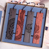 Four carved wooden bookmarks with tassel cords arranged in a blue gift box