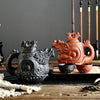Black and red dragon and phoenix ceramic teapots on a wooden table