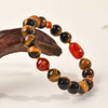 Close up of a yellow tiger eye bracelet with a red charm on a wooden stand