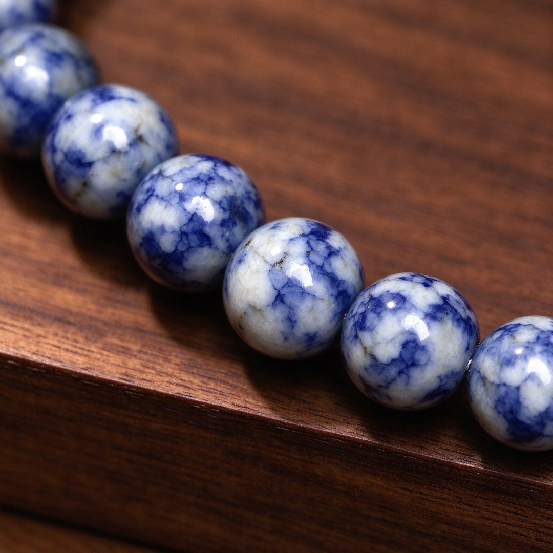 Close up view of round blue and white patterned stone beads on a wooden surface