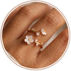 Close up of an adjustable metal ring with a white flower and clear stones on a finger