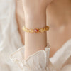 Close-up of a wrist wearing a golden rutilated quartz bracelet with a red center bead