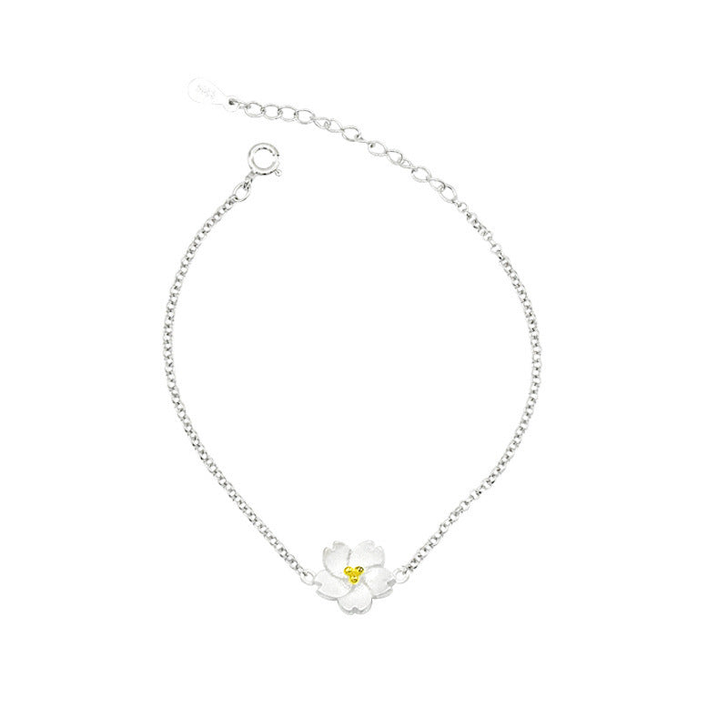 Silver plated bracelet with a white flower charm on a wrist