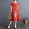 Woman wearing a red short sleeve midi dress with a white phoenix print
