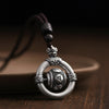 Close-up of a silver-tone copper pendant with a rotating center bead on a brown cord