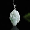 Close up of a pale green jade nine tailed fox pendant on a silver chain