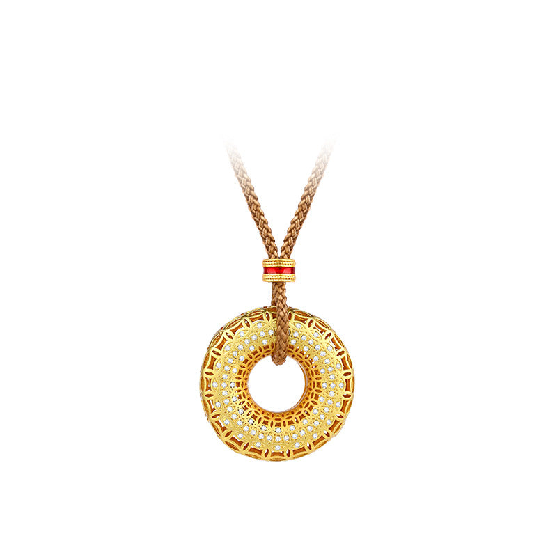 Gold-tone peace buckle pendant with coin pattern on a brown woven cord