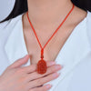 Red agate necklace with carved zodiac animal pendant worn against white shirt