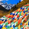 Rows of colorful Tibetan prayer flags strung across a mountain landscape
