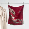 Red faux cashmere shawl with white lotus and wave pattern hanging on a rack