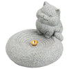 Hand holding a grey stone incense burner shaped like a sleeping cat