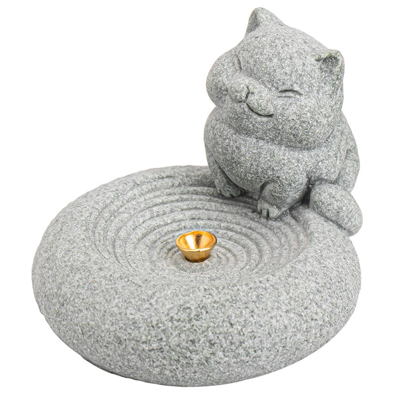 Hand holding a grey stone incense burner shaped like a sleeping cat