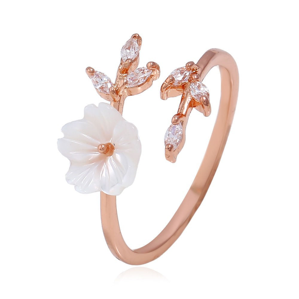 Close up of an adjustable ring featuring a white flower and leaf design