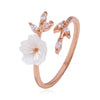 Close up of an adjustable ring featuring a white flower and leaf design