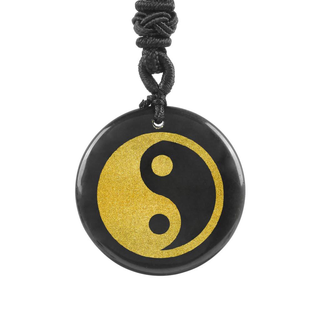 Close up of a polished natural crystal pendant with a gold Yin Yang symbol on a black cord