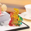 Colorful glass horse figurine sitting on a white surface with a book and cup nearby