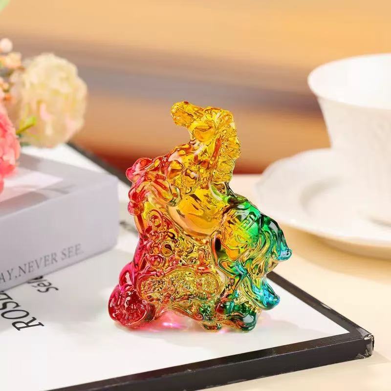 Colorful glass horse figurine sitting on a white surface with a book and cup nearby