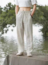 Man wearing light beige loose fitting linen pants standing by water