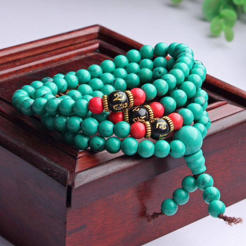 Multi-layer green turquoise bead mala bracelet with red accents on wooden box