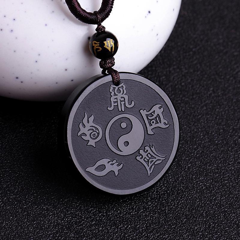 Round black pendant carved with Taoist mantras and a Yin Yang symbol on a brown cord