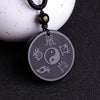 Round black obsidian pendant with Yin Yang and Taoist carvings on a cord