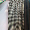 Black and white gingham pattern women's linen pants hanging on a rack