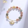 Gold-tone bracelet with mixed color rutilated quartz beads and a shell charm