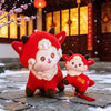 Red plush goat dolls with golden horns sitting on a stone surface with snow