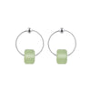 Close up of silver hoop earrings with square light green beads on a wooden surface
