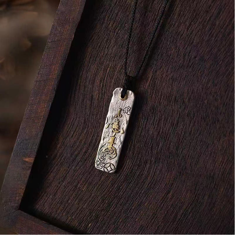 Rectangular silver pendant with gold Chinese characters on a black cord