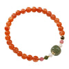 A beaded bracelet with red agate and a central green jade stone on a ceramic plate