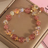 Pink strawberry quartz beaded bracelet with gold-tone money bag charm on a box