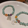Light green agate bead bracelet with a white jade-like peace buckle charm on a white plate