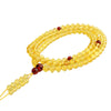 Coiled string of translucent yellow amber beads with red accents on a white background