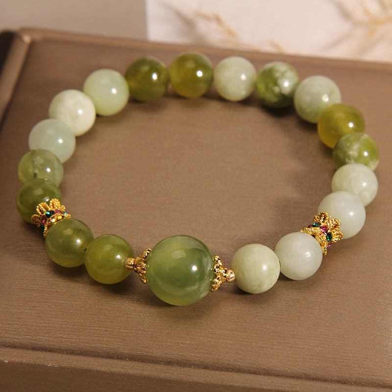 Green jade bead bracelet with gold flower spacers on a box