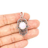 Silver tone Hamsa hand pendant with a central pink stone