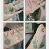 Hand holding several light green jade pendants including butterflies and flowers on white cords