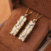 Two rectangular jade pendants with gold dragon and phoenix carvings on a brown display cushion