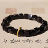 Close-up of a black square bead bracelet with a gold ring accent