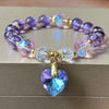 Purple beaded bracelet with gold tone spacers and a large pink heart charm held in hand