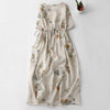Beige linen midi dress with orange floral print and drawstring waist laid flat on white background