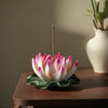 Pink and white ceramic lotus flower incense burner sitting on a wooden table