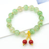 Green marbled glass bead bracelet with red cherry charm on white background
