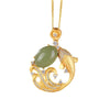 Gold-tone koi fish pendant with a smooth green stone resting on a soft jewelry box surface