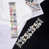 Close up of a silver-tone metal watch band decorated with colorful flower charms
