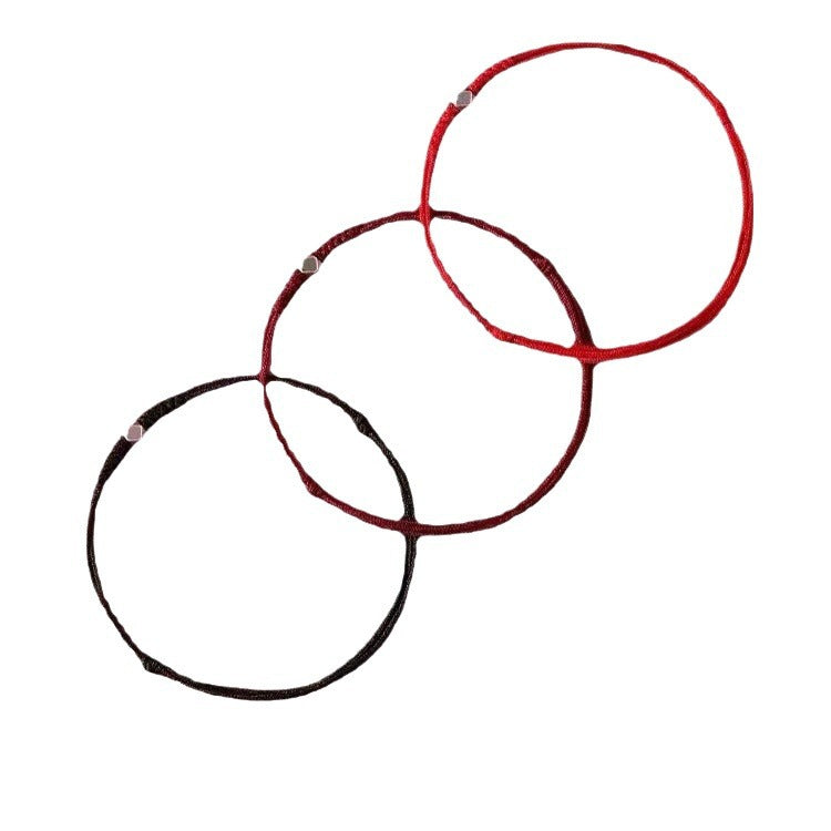 Three thin braided bracelets in red, wine red, and black with small silver-tone beads